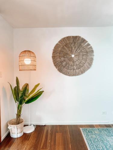 a living room with a potted plant and a lamp at Byron Butter Factory Apartments in Byron Bay