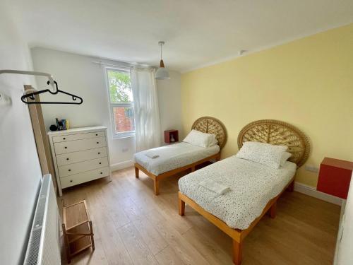 a bedroom with two beds and a dresser and a window at Beautiful Family Home in the Heart of Swansea in Swansea