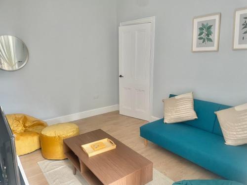 a living room with a blue couch and a table at Beautiful Family Home in the Heart of Swansea in Swansea