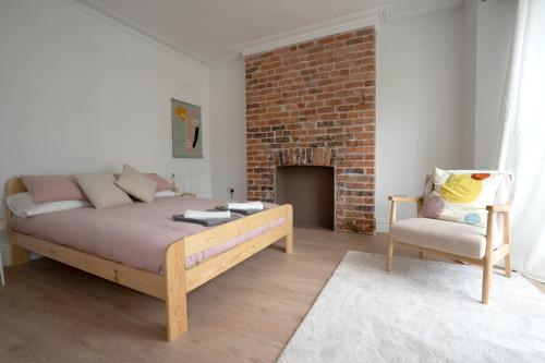 a bedroom with a bed and a chair and a brick wall at Beautiful Family Home in the Heart of Swansea in Swansea