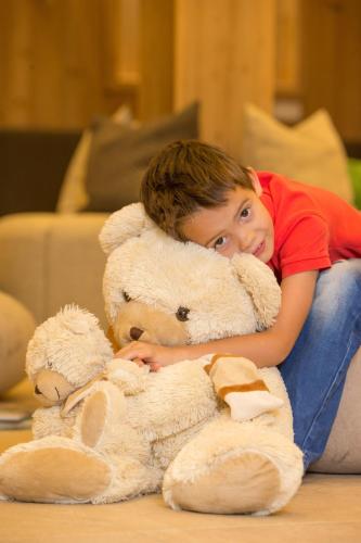 a young child laying on the floor with a large teddy bear at Hotel Stadt Wien in Zell am See