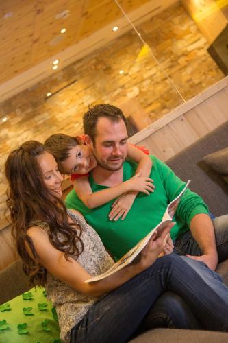 a man and woman sitting on a couch with a little girl at Hotel Stadt Wien in Zell am See