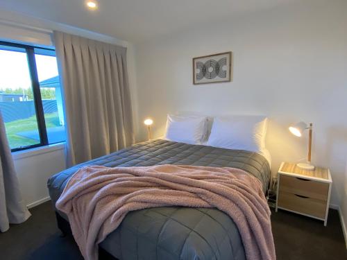 um quarto com uma cama com um cobertor em Uninterrupted Mountain Views em Twizel