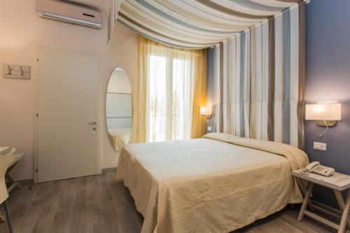 チェゼナーティコにあるHotel Triesteのベッドルーム1室(ベッド1台、大きな窓付)
