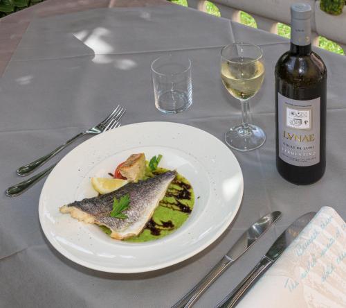 a plate of fish on a table with a bottle of wine at Hotel Ambra in Forte dei Marmi