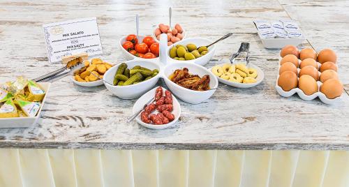 a table with bowls of fruits and vegetables on it at Hotel Ambra in Forte dei Marmi