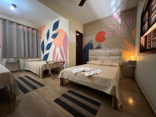 a room with two beds and a mural on the wall at Pousada Por do Sol in Quatis