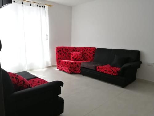 Dos sofás negros y rojos en una sala de estar. en Hermoso apartamento familiar con parqueadero privado, en San Gil