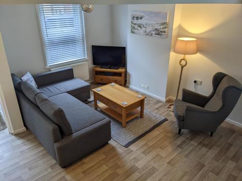 a living room with a couch and two chairs and a television at Ladybird Cottage in Weymouth