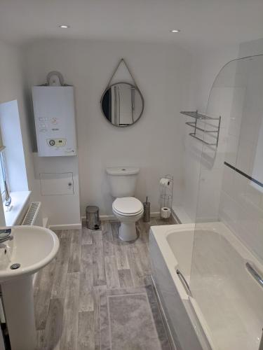 a bathroom with a toilet and a tub and a sink at Ladybird Cottage in Weymouth