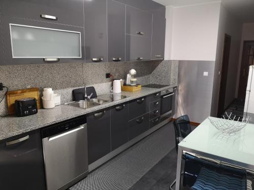 uma cozinha com armários cinzentos e um lavatório em Casa Valadim em Chaves