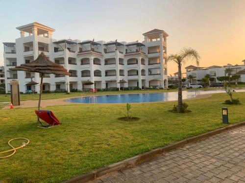 a large building with a pool in front of it at Chez Dany à Residence Beralmar in Asilah
