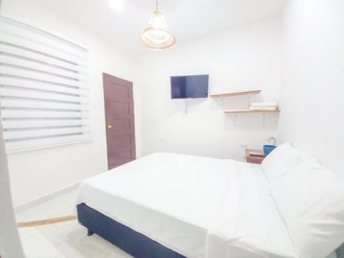 um quarto branco com uma cama e uma janela em Moon House Mompox em Mompós