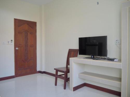 a living room with a tv and a wooden door at Pepa Guest House in Koh Tao