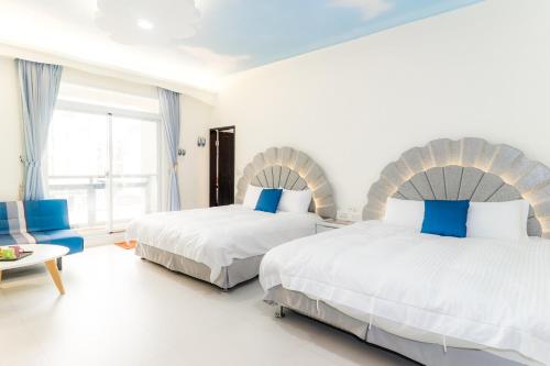 台東市にあるBooks & Woods Bed and Breakfastの白い部屋のベッド2台 ブルーアクセント