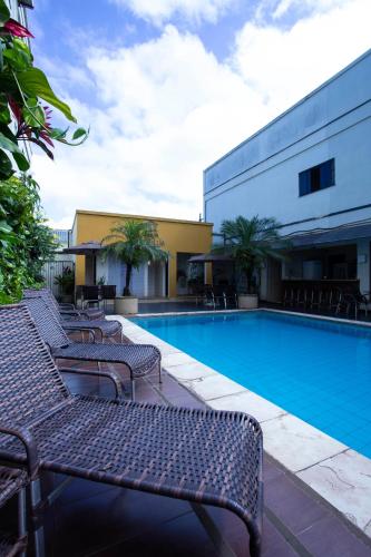 a swimming pool with benches next to a building at Atrium Confort Hotels in Parauapebas