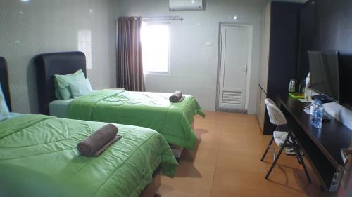 a hotel room with two beds and a television at Nasional Hotel in Gunungsitoli
