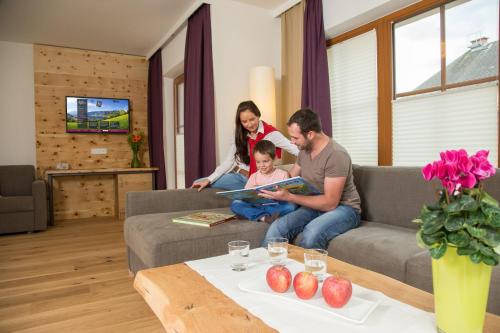 a family sitting on a couch in a living room at Hotel Stadt Wien in Zell am See
