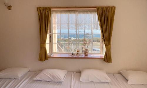 a bedroom with a bed and a window with a view at BBQ & Rental Villa Palm Village in Minamiboso