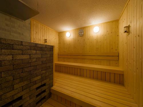 una sauna con paneles de madera y una pared de ladrillo en Art Hotel Narita en Narita