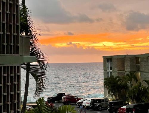 a sunset over the ocean with cars parked on the beach at Alii Villas Condominiums in Kailua-Kona