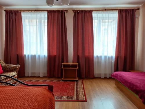 a bedroom with two beds and red curtains at Daugavpils City Centеr Apartment in Daugavpils