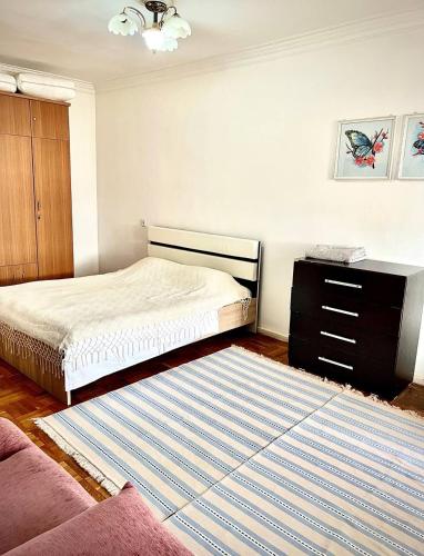 a bedroom with a bed and a dresser and a rug at Cozy 2 rooms apartment in the center, free WiFi in Dushanbe
