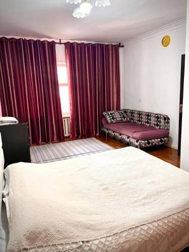 a bedroom with two beds and a couch and a window at Cozy 2 rooms apartment in the center, free WiFi in Dushanbe
