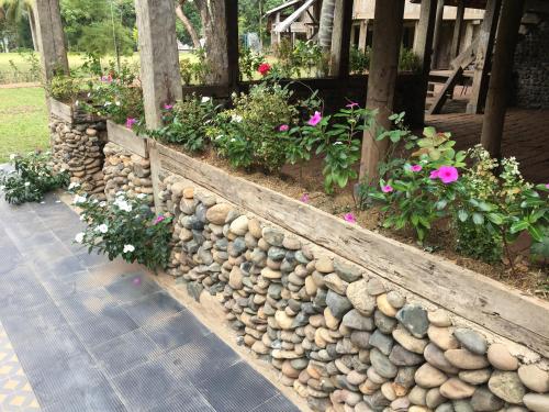 a stone retaining wall with flowers and plants at On The Mekong Resort in Luang Prabang