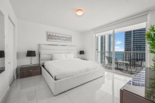 a white bedroom with a bed and a balcony at High Floor Ocean view Unit In Brickell in Miami