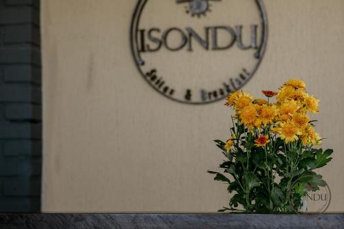 a vase of yellow flowers in front of a clock at ISONDU Suites & Breakfast in Puerto Iguazú