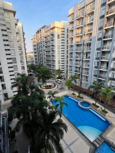um complexo de apartamentos com piscina e palmeiras em Resorts World Condo em Manilla