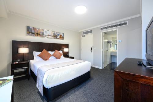 a hotel room with a bed and a flat screen tv at Hotel Grand Chancellor Adelaide in Adelaide