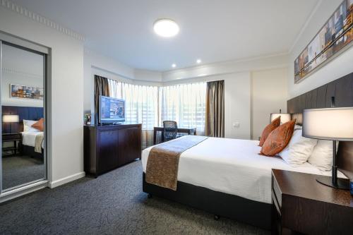 um quarto de hotel com uma cama grande e um espelho em Hotel Grand Chancellor Adelaide em Adelaide