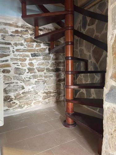 a wooden spiral staircase in a stone wall at Pelionature Maizonette in Makrinítsa