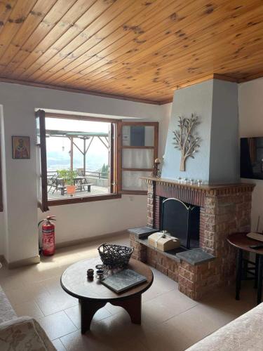 a living room with a fireplace and a table at Pelionature Maizonette in Makrinítsa