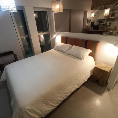 Un dormitorio con una gran cama blanca y una mesa en Ombu Loft Olivos, Vista al Rio in 
