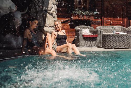 フューゲンにあるHotel Kohlerhofの二人の女の子が水の中に座ってスイミングプールに座っている