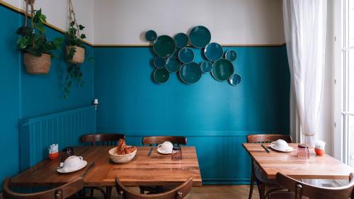 a dining room with blue walls and wooden tables and chairs at Hôtel du Dauphin in Lyon