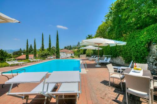 una piscina con mesas y sombrillas delante en Villa Faccioli Magnolia And Oleandro With Shared Pool - Happy Rentals, en Colognola ai Colli