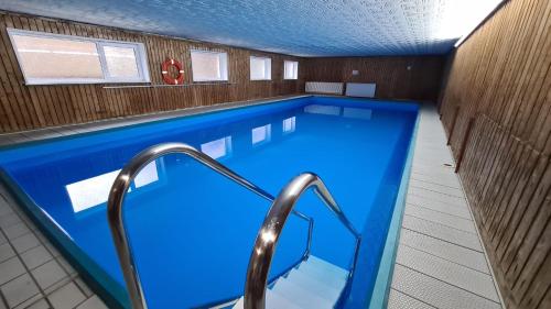 een groot zwembad met blauw water in een gebouw bij Ferienwohnung am Waldsee mit Schwimmbad in Gernsbach