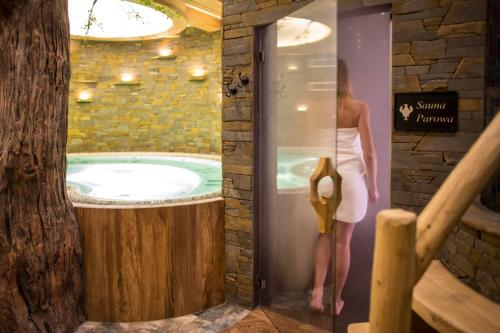 a woman standing in front of a jacuzzi tub at Pensjonat Orlik Mountain Resort&SPA in Bukowina Tatrzańska