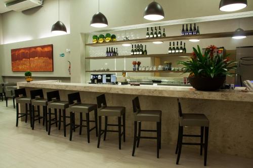 a bar in a restaurant with a bunch of stools at BH Raja Hotel in Belo Horizonte