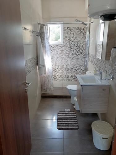 a bathroom with a sink and a toilet and a window at Ionian Golden Sun in Valanidorachi