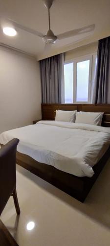 a bedroom with a large white bed with a window at AL NOOR SUITES in Salalah