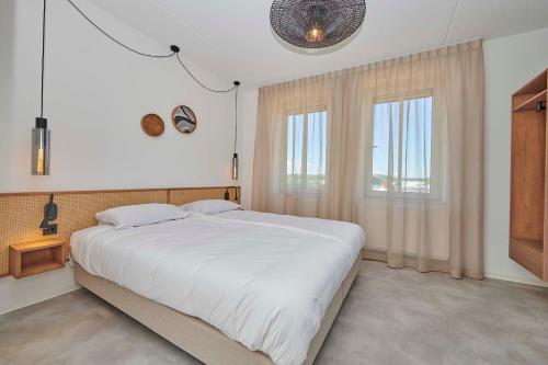 a bedroom with a large white bed and two windows at Parc Maasresidence Thorn Apartments in Thorn