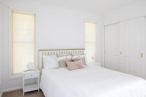 a white bedroom with a large white bed with pillows at Adorable 1-bedroom Kuzman Guesthouse in Mudgee