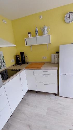 a kitchen with white cabinets and a clock on the wall at Ferienwohnung Fovere in Kall