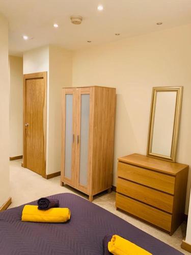 a bedroom with a bed and a dresser and a mirror at Executive Central Apartment in Sunderland