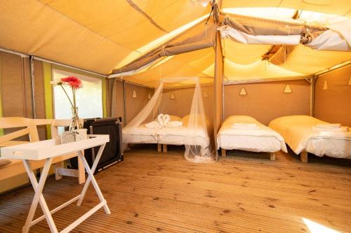 una camera con 2 letti e una scrivania in una tenda. di Blucamp a Campiglia Marittima